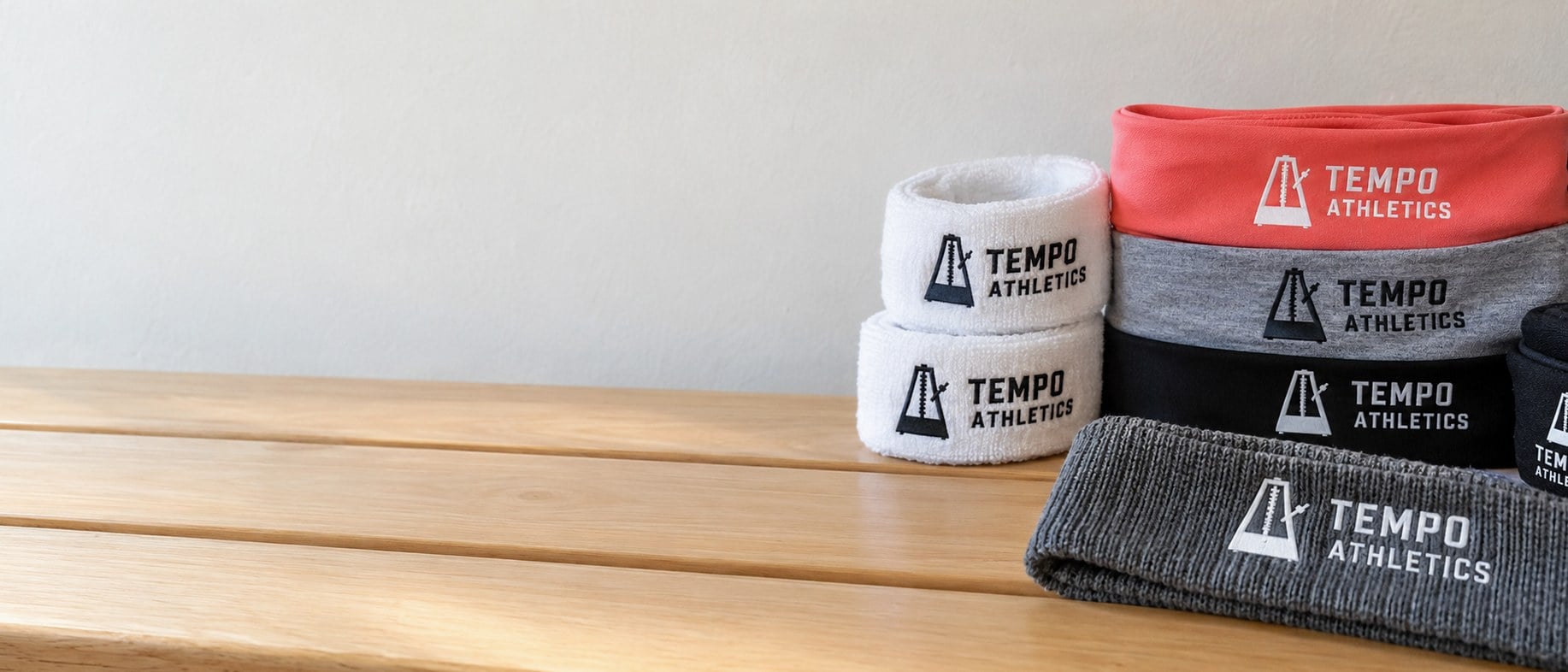 Custom printed and embroidered headbands laid out on a wooden gym bench
